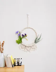 Dettaglio del cesto pensile nordico intrecciato a mano con fiori viola e frange boho