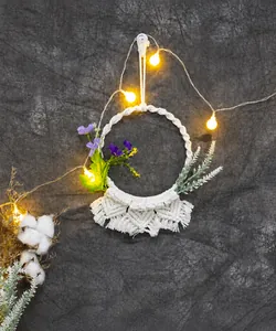 Dettaglio di decorazione murale boho fatta a mano con nappe bianche e fiori viola