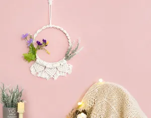 Dettaglio di macramè da parete fatto a mano con fiori viola in stile nordico chic