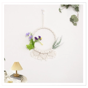 Dettaglio di decorazione murale boho in cotone intrecciato con nappe e fiori