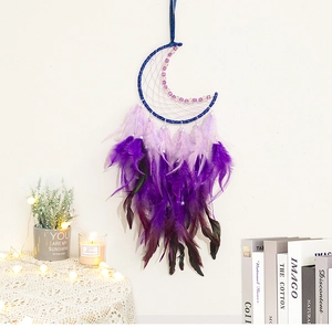Détail d'un attrape-rêves lune violette suspendu avec plumes dans une pièce cosy