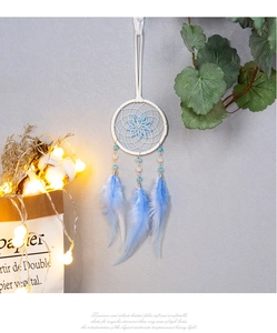 Détail d'un attrape-rêves bleu fait main avec plumes dégradées et perles au mur