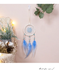 Détail d'un attrape-rêves bleu avec plumes et perles sur fond rose décoratif