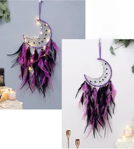 Detail of bohemian moon dream catcher with purple feathers and warm LED lighting
