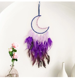 Vue détaillée d'un attrape-rêve lune avec plumes dégradées violettes sur un mur blanc