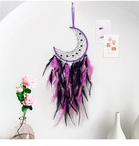 Detailed shot of moon-shaped macrame dreamcatcher with purple feathers and beads