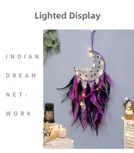 Detail of bohemian crescent moon dream catcher with purple feathers and warm LED lights