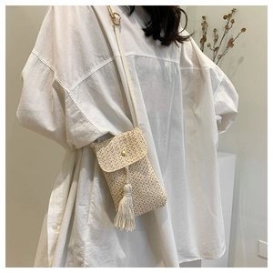 Detail of hand-woven straw mini crossbody phone bag with tassel and metal buckle detail