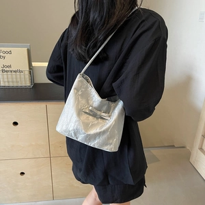 Borsa a spalla plissettata argento con fiocco indossata da una modella in un interno chic