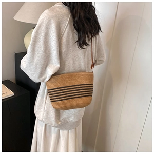 Détail d'un sac à bandoulière en paille tissée avec rayures noires et cuir marron