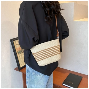 Detail of striped straw bucket bag featuring leather shoulder strap and metallic buckle