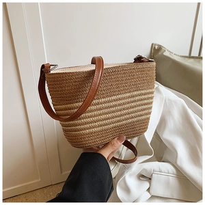 Détail du sac de plage en paille tressé avec motif rayé et anses en cuir marron