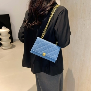 Gesteppte blaue Denim-Umhängetasche mit goldener Kette auf dem Rücken des Models