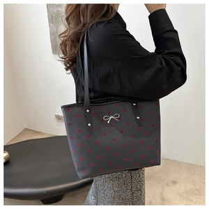 Detail of grey tote bag with red polka dots and metallic silver bow buckle detail