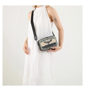 Detail of Halloween camera bag with bat prints and lettering on a white lace dress