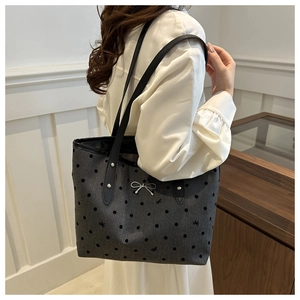 Close-up of grey tote bag with black flocking polka dots and silver bow detail