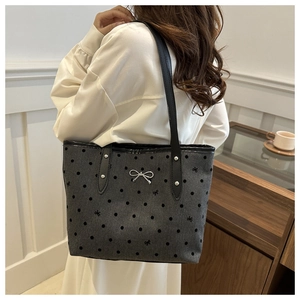 Close-up of heart polka dot canvas tote with silver bow and leather straps on model
