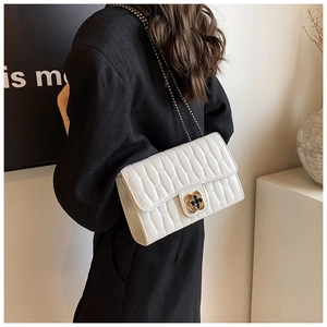 Close-up of white quilted crossbody bag featuring a golden floral clasp and metal chain