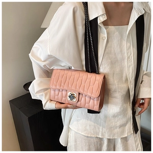 Detail of pink quilted crossbody bag featuring a silver metal flower clasp and chain strap