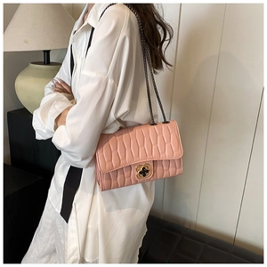 Pink quilted leather bag with floral metal clasp and chain strap detail on model