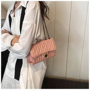 Detailed view of pink crossbody bag with quilted pattern and clover metal clasp