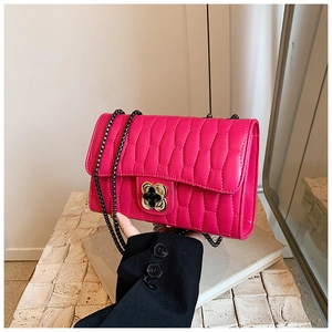 Detail of rose red crossbody bag with textured pleats and floral metal turn-lock