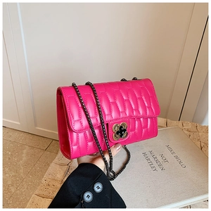 Detail of rose red quilted crossbody bag with flower clasp and black metal chain strap