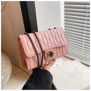 Detail of pink quilted crossbody bag with clover buckle and black chain strap