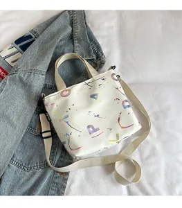 Detail of white canvas crossbody bag with colorful letter print and adjustable strap