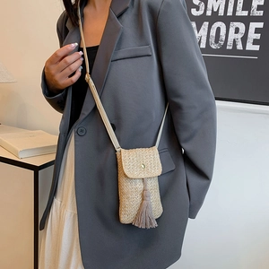 Petit sac de téléphone en paille tressée beige avec pompon porté avec style minimaliste