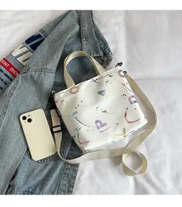 Detailed size comparison of a white tote bag with colorful letters next to a smartphone