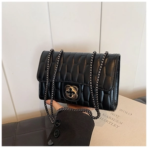Close-up of quilted black leather texture and exquisite metal flower buckle on handbag