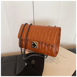 Detail of brown quilted leather crossbody bag with artistic flower shaped rotary lock