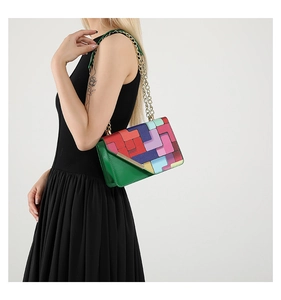 Detail of colorful geometric crossbody bag with gold chain strap on black dress