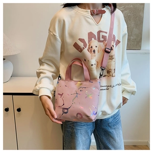 Détail d'un sac cabas en tissu rose avec motifs de lettres colorées et bandoulière tissée