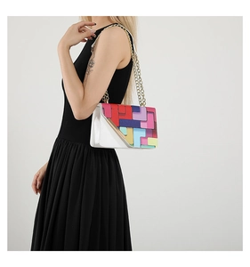 Detail of colorful geometric pattern crossbody bag with gold chain strap on model