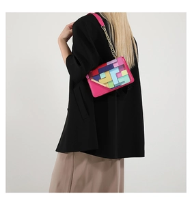 Detail of pink shoulder bag with colorful geometric blocks and golden chain strap