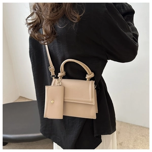 Detail view of beige crossbody bag with knotted handle and mini pouch on model