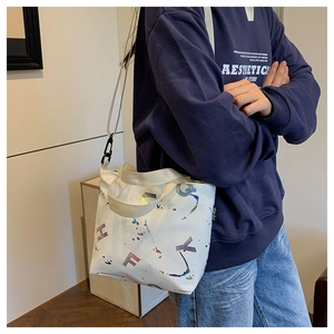 Détail du sac cabas en toile blanche avec lettres colorées et bandoulière amovible