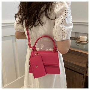Close-up of bright pink shoulder bag with woven handle and small detachable coin pouch