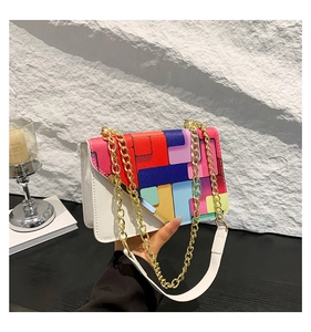 Detail of color-block flap and gold chain strap on white minimalist square crossbody bag