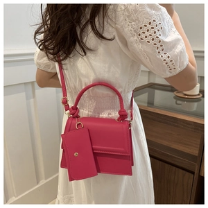 Close-up of rose pink crossbody bag featuring knotted handle and matching mini pouch