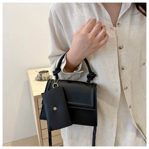 Detail of black crossbody bag with knot handle and a detachable mini coin purse pendant