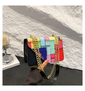 Detail of colorful geometric patchwork on black leather bag with gold chain strap