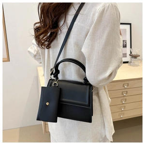 Detail of black leather crossbody bag with knot handle and small detachable coin purse