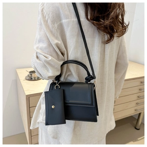 Minimalist black PU leather crossbody bag with mini pouch and gold hardware shown on a model