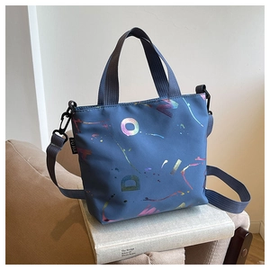 Détail d'un sac cabas en nylon bleu avec lettres dégradées et bandoulière réglable