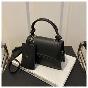 Detail of black crossbody bag with knotted handle and matching mini envelope pouch