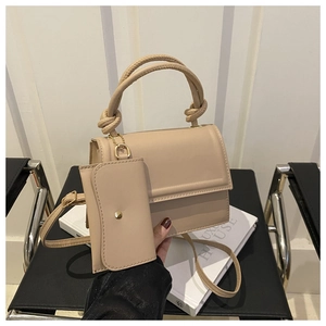 Detail of beige leather handbag featuring a unique knotted handle and matching mini pouch
