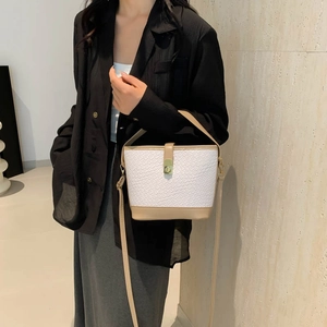 Chic two-tone woven bucket bag with leather trim and gold twist lock on model
